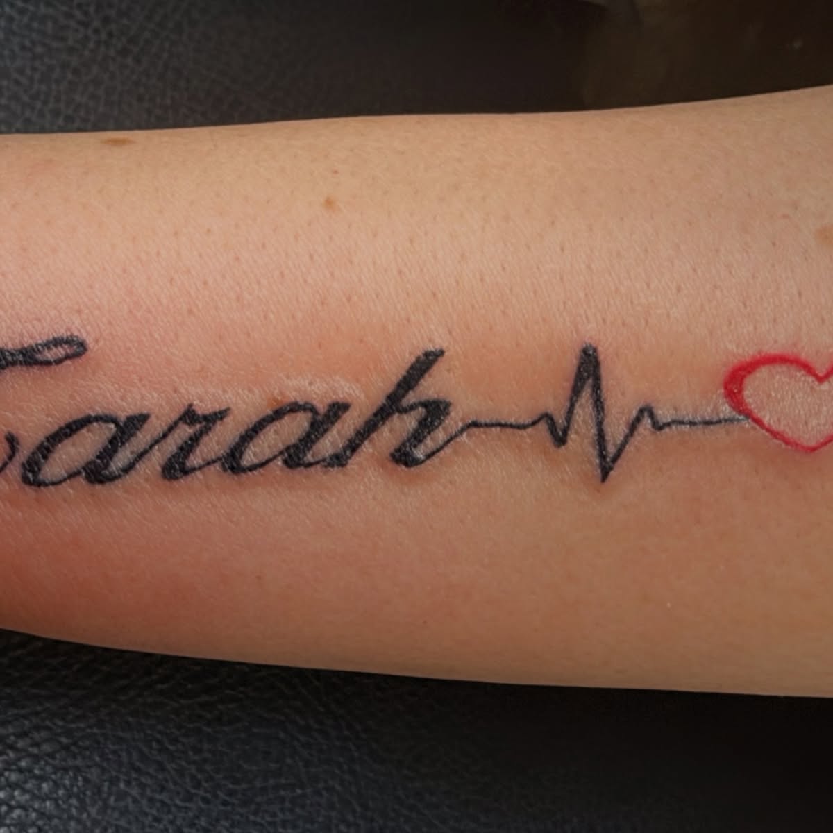 Schriftzug-Tattoo mit Herzschlaglinie, Arbeit von Adonis Tattoo & Piercing
