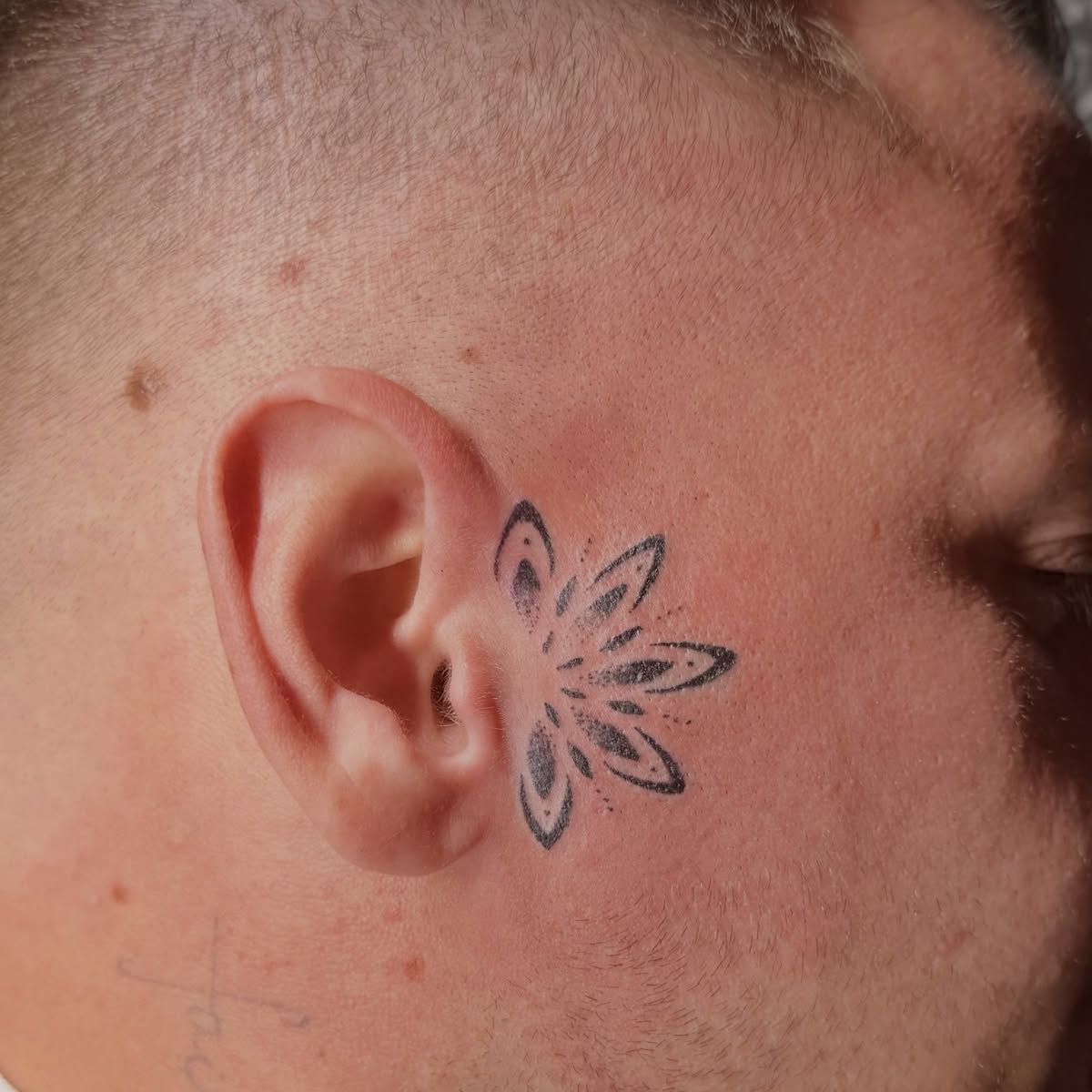 Feines Blumen-Tattoo hinter dem Ohr